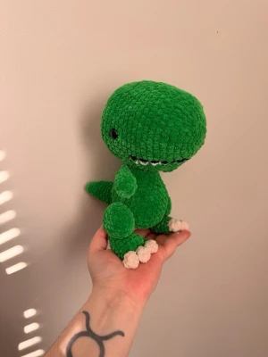 Grön virkad dinosaurie mjukisdjur - Supergullig grön virkad dinosaurie i mjukt garn med vita klor och svarta ögon. Perfekt som dekoration eller present till någon som gillar söta och unika gosedjur.