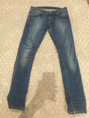 Blå slim fit jeans från Nudie Jeans - Snygga blå slim fit jeans från Nudie Jeans med klassisk femficksdesign. Jeansen har normal midja och raka ben.