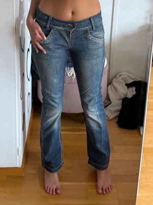 Blå bootcut jeans från Miss Sixty - Säljer ett par blå bootcut jeans från Miss Sixty, modell KAREN. Jeansen har låg midja, klassiska fickor och snygga slitningar framtill. Perfekta för dig som gillar en retro och avslappnad stil.