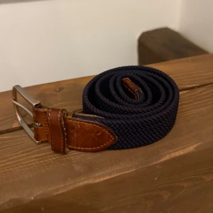 Mörkblått flätat bälte med läderdetaljer - Saddler bälte Marstrand 90cm. Nypris 595kr