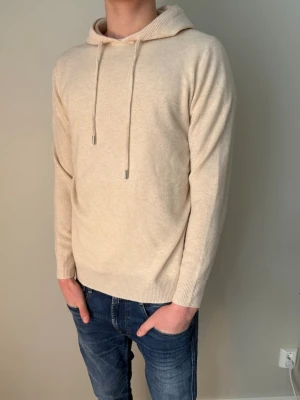 Kashmir/ merinoull hoodie  - Säljer denna i princip oanvända hoodien i en sjukt skön Kashmir/ merinoull blandning, 70/30. Hoodien passar storlek M och är sand/ biegefärgad. Han på bild är 184 cm lång. Hör av er vid fler bilder/ frågor! 