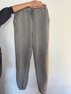 Grå mjukisbyxor ASOS tall - Säljer ett par klassiska grå mjukisbyxor med resår i midjan för skön passform. Byxorna har även resår vid bensluten och är gjorda i mjukt, stretchigt material. Perfekta för chill dagar hemma eller till träningen. Byxorna är från ASOS tall så de passar långa tjejer. Byxorna är noppriga.