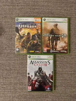 3 Xbox 360 spel: Outfit, MW2, AC2 - Tre Xbox 360-spel: The Outfit från THQ, Call of Duty: Modern Warfare 2 från Activision och Assassin's Creed II från Ubisoft. Alla spel har gröna plastfodral och tydliga omslag med actionfyllda motiv. Perfekt för dig som gillar action och äventyr.
