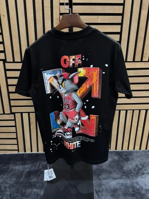 Märkeskläder  - Svart t-shirt  med tryck av Tom i basketkläder på ryggen och färgglada detaljer. Framtill finns en liten metallbricka med logga. Klassisk passform och rund halsringning.