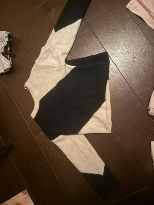 Stickad tröja med svart och beige mönster - Snygg stickad tröja i beige och svart med coolt diagonalt mönster. Tröjan har rund halsringning och långa ärmar. Perfekt för dig som gillar en stilren men ändå unik look. Materialet känns mjukt och bekvämt.