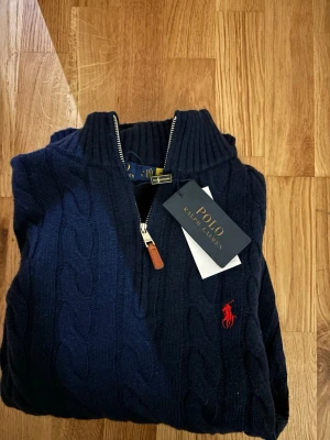 Raulph lauren quarter zip  - En fin quarter zip från Ralph lauren. Den har fortfarande prislappen kvar då den är oanvänd och är i den populära färgen navy/mörkblå. Storleken är i Xl men sitter som en L. Fick den i present men har ej funnit användning till den. Kan sjunka i pris vid snabba affärer!