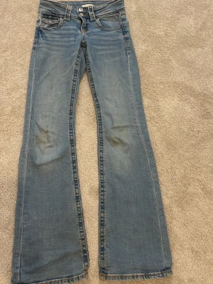 Blå bootcut jeans från Gina Tricot - Säljer ett par klassiska blå bootcut jeans från Gina Tricot. Jeansen har fem fickor, knapp och dragkedja framtill samt snygga slitningar och ljus tvätt. Perfekta för dig som gillar en avslappnad och trendig look. Storlek 146❤️