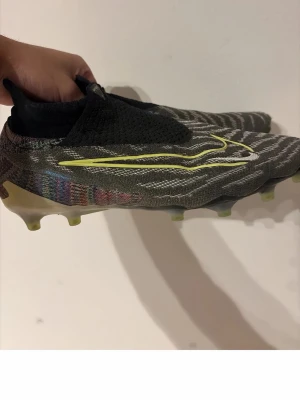 Nike Mercurial Superfly fotbollsskor - Säljer ett par Nike Mercurial Superfly fotbollsskor med grå och svarta mönster, gula detaljer och stickad strumpa. Skorna har en låg vikt, mönstrad ovandel i syntetmaterial och genomskinlig sula med fasta dobbar för gräsplan. Perfekta för dig som vill ha speed och kontroll på planen.