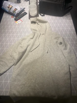 Merino hoodie  - En enkel och stilren ljusgrå hoodie med huva och dragsnören. Hoodien har en avslappnad passform och är tillverkad i ett mjukt material som känns skönt mot huden. Perfekt för en chill och casual look.