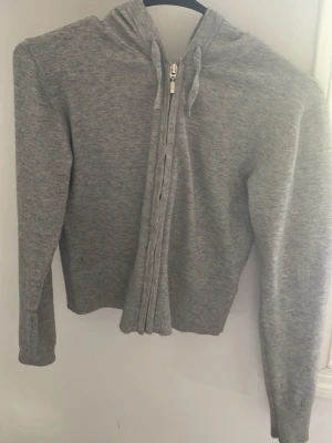 Grå hoodie med dragkedja - Snygg grå hoodie med dragkedja framtill och huva. Tillverkad i mjukt, stretchigt material som känns skönt mot huden. Perfekt för en avslappnad och casual stil. Klassisk passform och neutralt utseende som passar till det mesta.