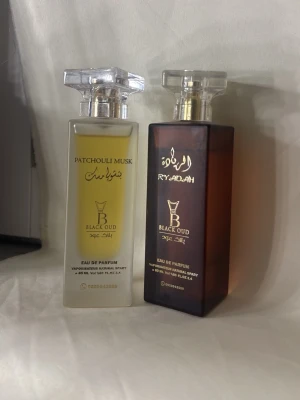 Black Oud Patchouli Musk & Ryadah parfym - Parfymer från Dubai Två exklusiva parfymer från Black Oud: Patchouli Musk i en transparent rektangulär flaska med silverdetaljer och Ryadah i en mörkbrun flaska med gulddetaljer. Båda har tydliga orientaliska inslag och elegant design med guldtext. Säljs var sig 650 styck