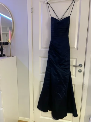 Marinblå långklänning med smala band - Säljer min superfina balklänning från JJ house. Den har dubbla lager tyg, slits och knyt rygg. Väldigt fint skick. Strl 32/xxs 💗skriv om ni har frågor eller vill ha fler bilder. Nypris: ca 1500kr