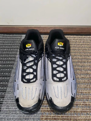 Nike Air Max Plus Tn svart/vit - Nike Air Max Plus Tn sneakers i svart och vitt med reflekterande detaljer. Skorna har en mesh-överdel, svarta syntetiska paneler och tydlig Air Max-dämpning i sulan. Klassisk Tn-logga på plösen och coolt mönster längs sidorna. Perfekta för dig som gillar streetwear. Skick som på bilderna.