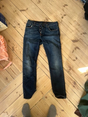 Mörkblå jeans från Nudie Jeans - Säljer ett par nudie jeans grim trim i storlek 32/32.  Defekter förekommer därav priset😃.                        Mått: midja 40, längd 106, benöppning 18