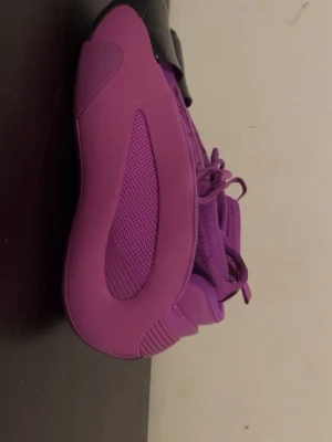 Lila sneakers Adidas Yeezy QNTM - Säljer ett par lila Adidas Yeezy QNTM sneakers med futuristisk design och meshpaneler på sidorna. Skorna har snörning och en chunky sula som ger en sportig vibe. Perfekta för dig som vill sticka ut med färg och stil.