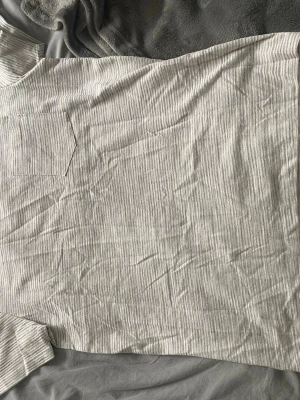 Randig t-shirt från Kappahl - Säljer en ljusgrå och vit randig t-shirt från Kappahl med korta ärmar och rund halsringning. Materialet är mjukt och ribbat, bröstficka på vänster sida. 