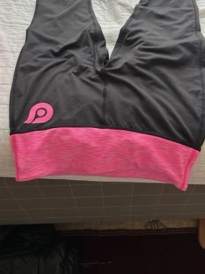 Rosa träningsset från Pierre Robert - Säljer ett snyggt träningsset från Pierre Robert med svart och rosa tights samt matchande rosa zip-jacka. Båda plaggen har logga och är tillverkade i stretchigt funktionsmaterial som andas. Perfekt för löpning eller gym.