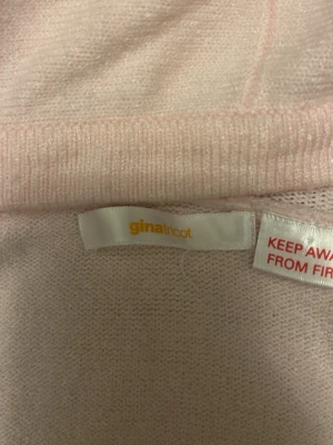 Ljusrosa stickad tröja Gina Tricot - Mysig ljusrosa stickad tröja från Gina Tricot med långa ärmar och ribbade muddar. Tröjan har en enkel och stilren design, perfekt för att hålla värmen. Materialet är mjukt och bekvämt, vilket gör den skön att bära hela dagen.