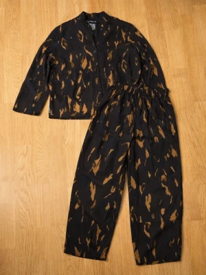 Svart & Brun Abstrakt Tvådelat Set - Bekvämt matchande set som kan användas som nattkläder eller avslappnade loungepyjamas. Matchande byxor Resår (gummiband) bak i midjan för extra komfort Avslappnad passform