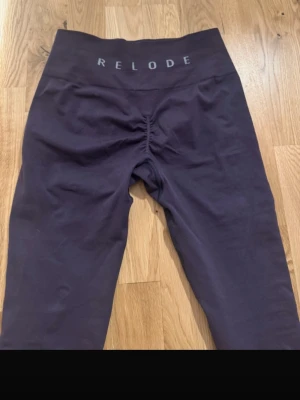 Relode tights/ leggings  - Snygga mörklila leggings från Relode med hög midja och scrunch-detalj bak. Tillverkade i ett stretchigt material som sitter skönt och formar sig efter kroppen. Perfekta för träning, det är XS men passar en S ( den är köpt på vinted och är endast testad, säljer för att den inte passa mig)