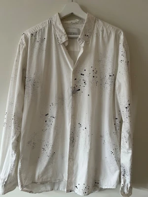 Vit skjorta med svart stänkmönster Denimes - Säljer en vit långärmad skjorta från Denimes med svart stänkmönster för en edgy look. Mycket bra skick! 
