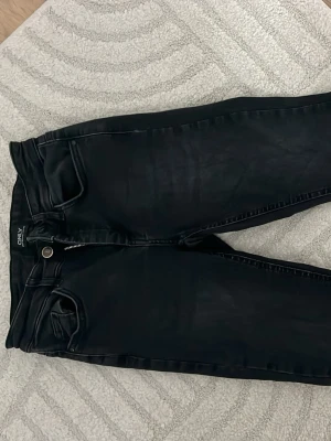 Svarta bootcut jeans med stretch - Säljer ett par svarta bootcut jeans med normal midja och klassiska bakfickor. Jeansen har en smal passform och är tillverkade i stretchigt material för extra komfort. Perfekta till en avslappnad eller trendig look.
