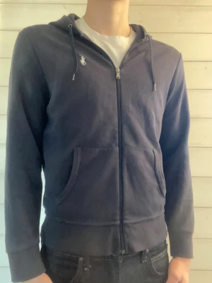Mörkblå hoodie från Polo Ralph Lauren - Mörkblå hoodie med dragkedja från Polo Ralph Lauren. Tröjan är i fint skick men inga skador eller fläckar. Skriv om ni undrar något eller har några frågor!