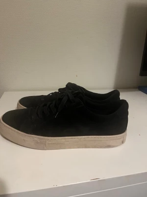 Svarta låga sneakers med vit sula - Säljer ett par svarta Paul 2.0 sneakers från Vagabond som är använda under cirka 3 månader och är i bra skick. De är i mocka med snörning och låg profil och säljs då de är för stora.
