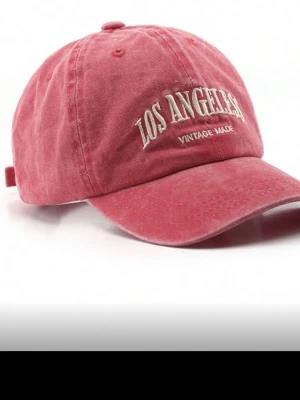 Röd keps med Los Angeles-brodyr - Säljer en snygg röd keps med böjd skärm och broderad text 'LOS ANGELES VINTAGE MADE' framtill. Kepsen har en avslappnad vintage-look och är tillverkad i bomullstyg. Perfekt accessoar för en cool streetwear-stil.