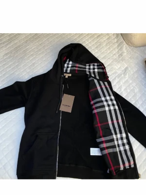 Svart hoodie från Burberry med dragkedja - Passer från 50 kg till 75kg och är helt by med tag