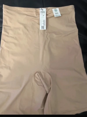 Beige high waist shapewear boxer - Säljer ett par beige shapewear boxers från H&M med hög midja. Gjorda i en blandning av återvunnen polyamid och elastan för en smidig och bekväm passform. Perfekta under tighta kläder för en slät siluett.