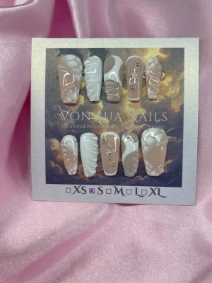 IvorySkin (S);Medium Ballerina - Handgjorda press-on naglar i storlek S: 15 mm, 11,5 mm, 12 mm, 11 mm, 9 mm . Naglarna har en beige och vit bas med handmålade mösnter, 3D-detaljer och silverfärgade stenar samt stjärndekorationer. Formen är medium lång och ballerinaform. Perfekt för dig som vill ha unika och trendiga naglar.