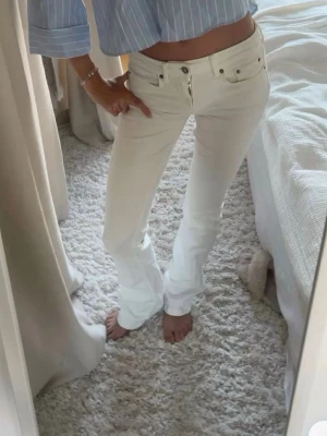 Vita bootcut jeans med låg midja - Säljer ett par vita bootcut jeans med låg midja. Jenasen är från subdued och just denna modell går inte att köpa längre. Jeansen har utsvängda ben och stängs med knapp och dragkedja. Perfekta för en trendig och fräsch look. Materialet är mjukt och följsamt.