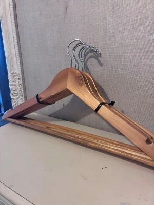 Trägalgar med metallkrok 5st - Säljer ett set med fem galgar i trä med metallkrok. Galgarna har en klassisk form och är ljusbruna med slät yta. Perfekta för att hänga upp skjortor, jackor eller byxor i garderoben. 