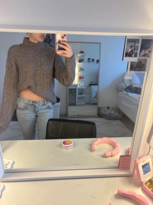 Brun kabelstickad croppad tröja - Säljer en brun kabelstickad croppad tröja med hög krage och långa ärmar. Tröjan har en avslappnad passform och är perfekt för lager på lager. Materialet ser mjukt och mysigt ut, perfekt för kyligare dagar. Helt ny och har ej använt den.