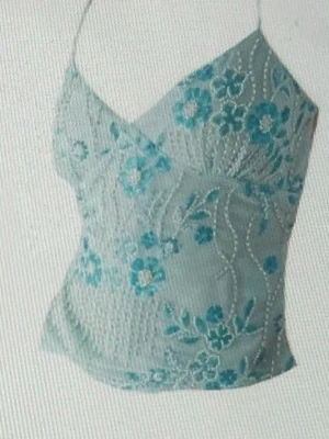 Blommig spetslinnetopp i ljusblått - Söt ljusblå linnetopp med tunna axelband och v-ringning. Toppen är dekorerad med blommigt spetsmönster i blå toner och har en feminin, figurnära passform. Perfekt för varma dagar eller som ett lager under en kavaj.