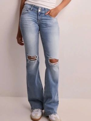 Ljusblå bootcut jeans med slitningar - Säljer ett par ljusblå bootcut jeans med slitna hål över knäna och klassisk femficksdesign. Jeansen har en något utsvängd passform och är tillverkade i denim med en snygg tvätt. Perfekta för en avslappnad och trendig look.