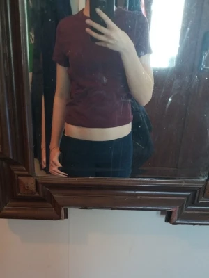 Vinröd croppad t-shirt i bomull - En enkel och stilren vinröd croppad t-shirt från Gina Tricot. T-shirten har korta ärmar, rund halsringning och är gjord i mjuk bomull. Perfekt till jeans eller kjol för en avslappnad look.