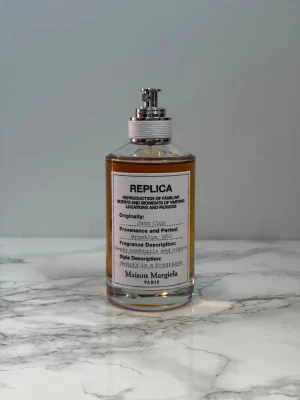 Maison Margiela Jazz Club parfym - Maison Margiela Jazz Club är en elegant parfym i en genomskinlig glasflaska med metallisk spraypump och vit etikett. Doften har inslag av läder, cocktails och cigarrer, och flaskan har en varm bärnstensfärgad vätska. Perfekt för dig som gillar unika och minnesvärda dofter. Endast provsprutat