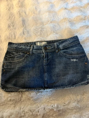 Mörkblå jeanskjol  - Säljer en snygg mörkblå jeanskjol i storlek 36! Kjolen har en kort, rak passform och slitna detaljer. Dragkedjan är tyvärr trasig på kjolen men går att fixa enkelt!💗💗