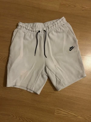 Vita Nike shorts med snörning - Säljer mina vita  Nike tech shorts då de är för små. Inga defekter skriv om ni har frågor.