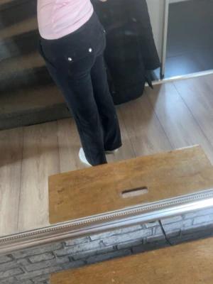 Svarta mjukisbyxor med fickor - Säljer ett par svarta mjukisbyxor med raka ben och dragsko i midjan. Byxorna har fickor både fram och bak, där bakfickorna har knappar i silverfärg. Perfekta för chill dagar och riktigt sköna att ha på sig. Dem är lite kortare en vanligt, en silver grej har tappats på snöret annars inget speciellt 