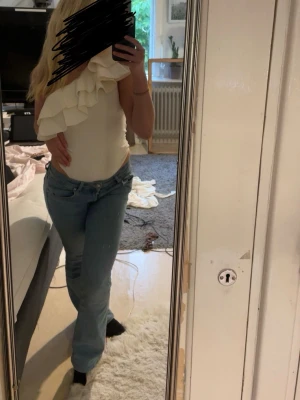 Vit body med volang - Säljer en vit, ärmlös body med omlott-design och stora volangdetaljer över ena axeln. Toppen har en tight passform. Den är aldrig använd. Kommer från Zara och är i storlek S. 