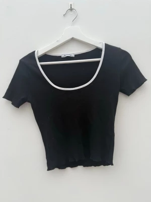 Svart ribbad topp från Zara Trafaluc - Svart ribbad topp från Zara med vit kant . Kortärmad och croppad modell som sitter tight. 