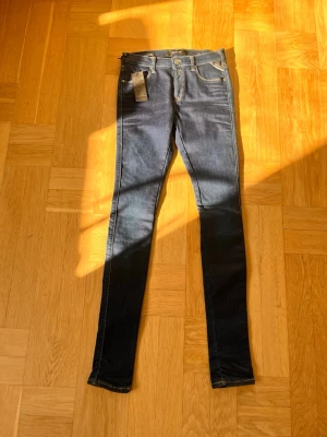 Mörkblå skinny jeans från Replay - Snygga mörkblå skinny jeans från Replay med klassisk femficksdesign och smala ben. Jeansen har silverfärgade knappar och dragkedja samt kontrastsömmar. Materialet är stretchigt denim som sitter tajt och bekvämt. Perfekta för en trendig och avslappnad look.