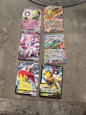 Pokémonkort GX och VMAX mix - Säljer ett set med sex Pokémonkort i GX, V och VMAX-versioner. Bland korten finns Gardevoir, Tyranitar, Sylveon, Terapagos, Blaziken och Raikou. Korten har färgstarka illustrationer och holografiska effekter. Perfekt för samlare eller Pokémonfans som vill utöka sin kortsamling.