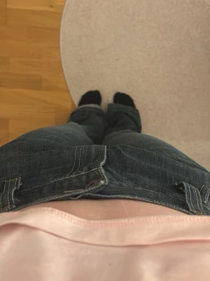 Mörkblå bootcut jeans med kontrastsömmar - Säljer ett par mörkblå bootcut jeans med snygga kontrastsömmar och klassiska fem fickor. Jeansen har låg midja och är tillverkade i ett robust denimtyg. Perfekta för en avslappnad och trendig look. Pris kan alltid diskuteras
