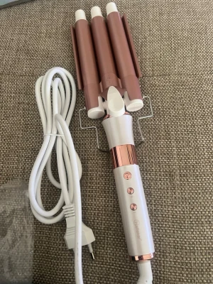 Vågig locktång i roséguld och vitt - Säljer en elektrisk locktång med tre cylindrar i roséguld och vitt handtag. Tången har flera knappar för temperaturinställning och lång vit sladd. Perfekt för att skapa snygga beach waves och volym i håret. nyskick pris går att diskutera 💕💕  Har fler vågtångar som jag säljer 