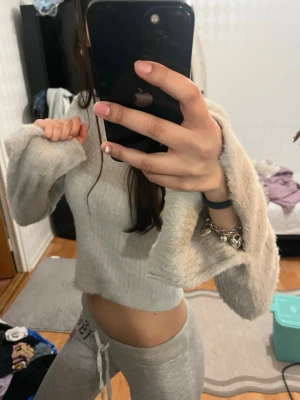 Ljusgrå fluffig stickad tröja  - Supermjuk och fluffig ljusgrå stickad tröja från Divided. Tröjan har croppad passform, långa ärmar och rund halsringning. Perfekt för dig som gillar en chill och cozy vibe. Materialet är mjukt och ger en avslappnad look.