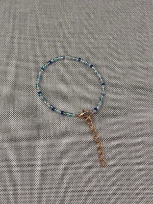 Blått pärlarmband med guldlås - Handgjort armband med små pärlor i olika blå nyanser. Armbandet har ett justerbart guldfärgat kedjelås. Perfekt för dig som gillar enkla men trendiga accessoarer.